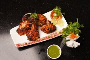 Deliciously grilled chicken with mint chutney, herbs, and lemon slices. Perfect dinner dish.